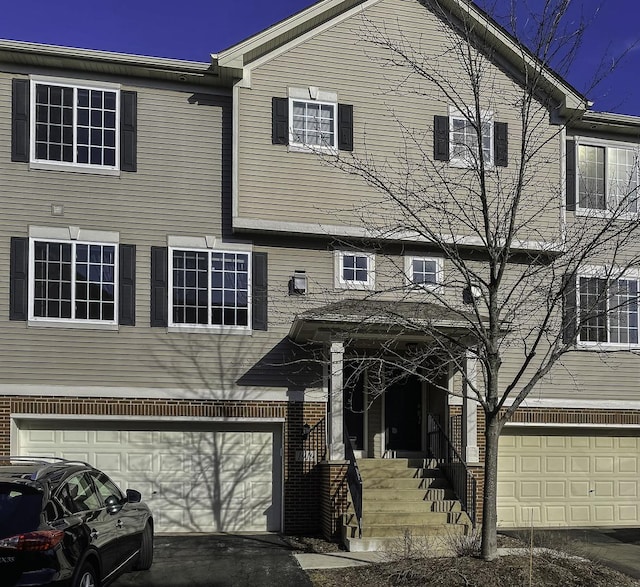 townhome / multi-family property with a garage and brick siding