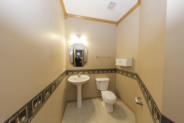 half bathroom featuring crown molding, toilet, baseboards, and visible vents