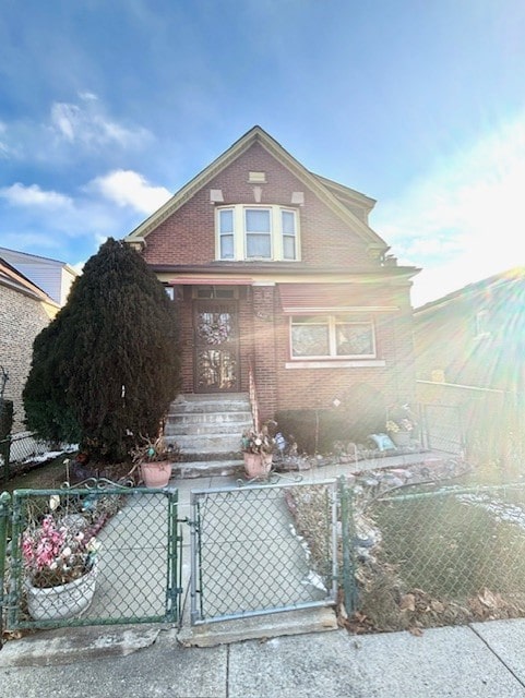 view of front of home with a fenced front yard, a gate, and brick siding