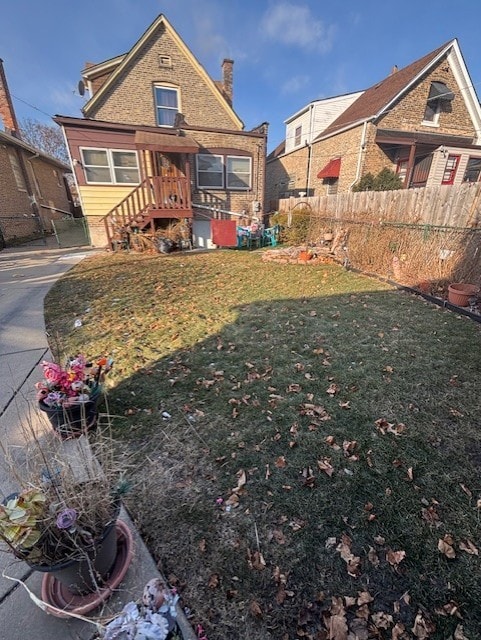 exterior space with a yard, brick siding, fence, and a chimney