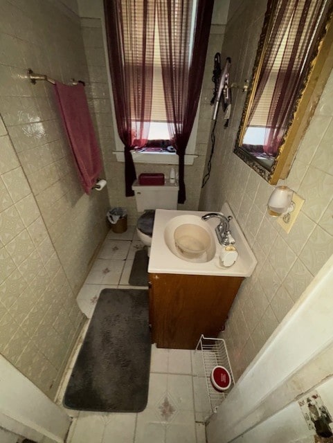 full bathroom featuring a shower, toilet, tile patterned floors, vanity, and tile walls