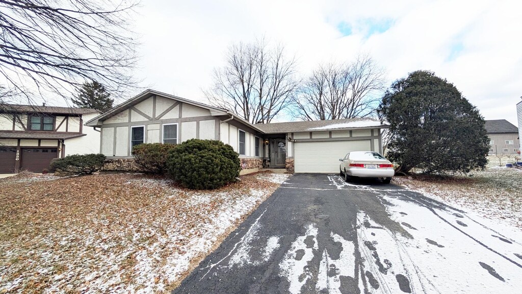 view of front of property with aphalt driveway, an attached garage, and stucco siding