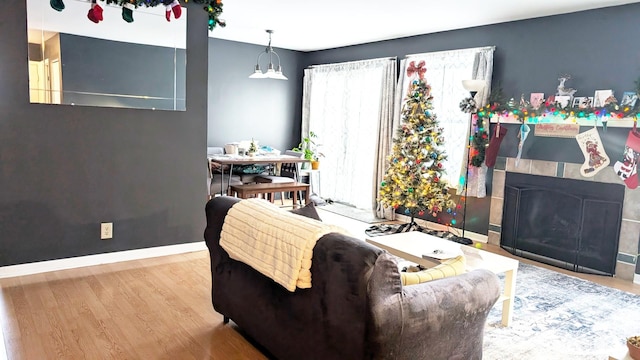 living area featuring a fireplace, wood finished floors, and baseboards