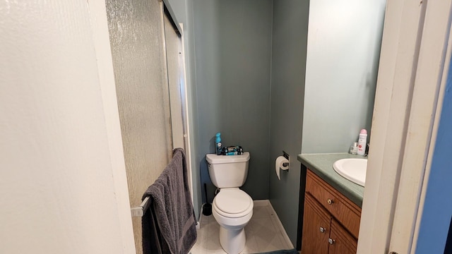 bathroom with tile patterned flooring, baseboards, vanity, and toilet