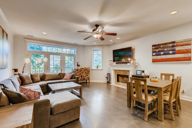 living area with ornamental molding, a tiled fireplace, wood finished floors, recessed lighting, and baseboards