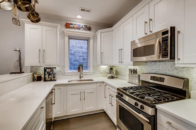 kitchen with visible vents, a sink, stainless steel appliances, white cabinets, and decorative backsplash