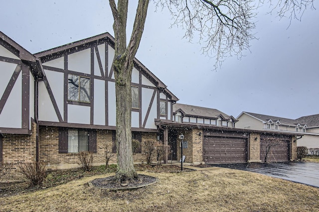 tudor house with aphalt driveway, brick siding, and stucco siding