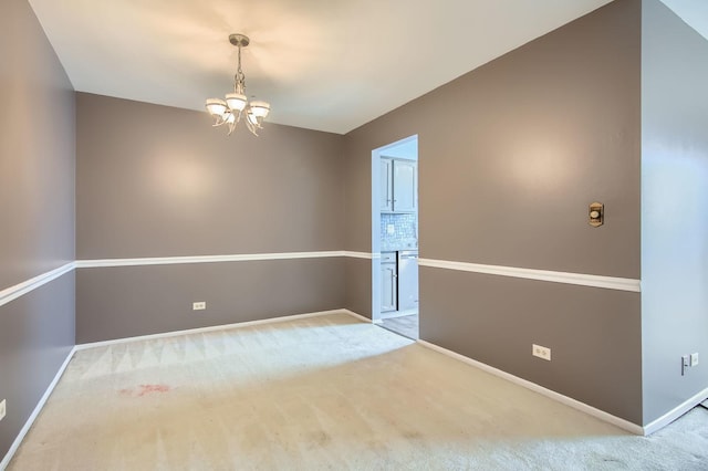 spare room featuring an inviting chandelier, carpet, and baseboards