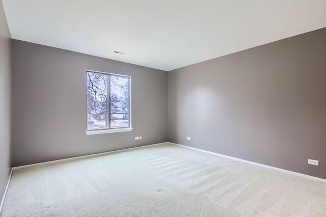 empty room featuring light carpet, baseboards, and visible vents