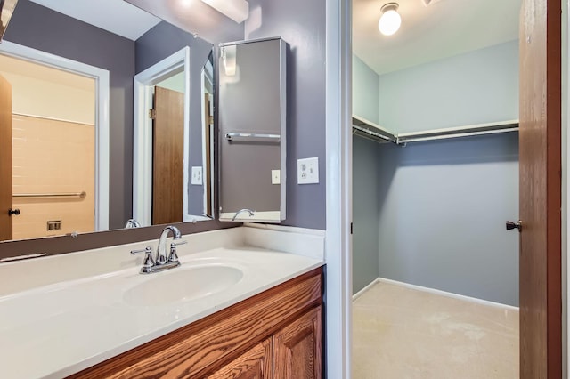 bathroom featuring a walk in closet, vanity, and baseboards