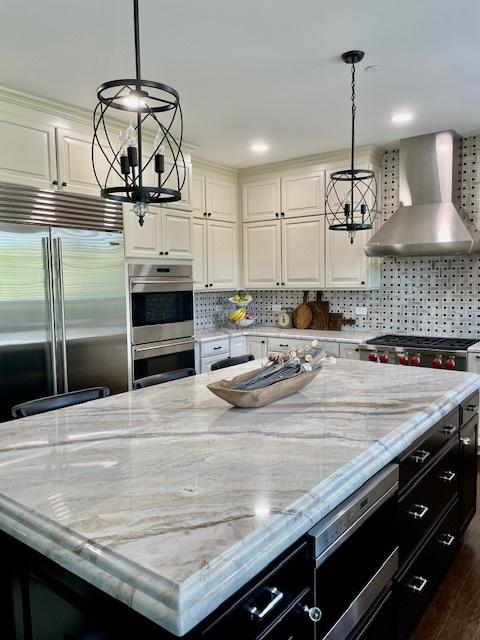 1860 Lake Charles Dr, Vernon Hills, IL 60061 - kitchen featuring wall chimney range hood, built in appliances, a chandelier, a large island, and white cabinetry