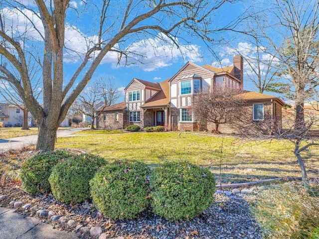 view of front of home with brick siding, a chimney, and a front yard