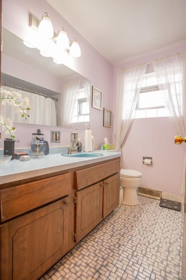 bathroom featuring brick floor, visible vents, vanity, and toilet