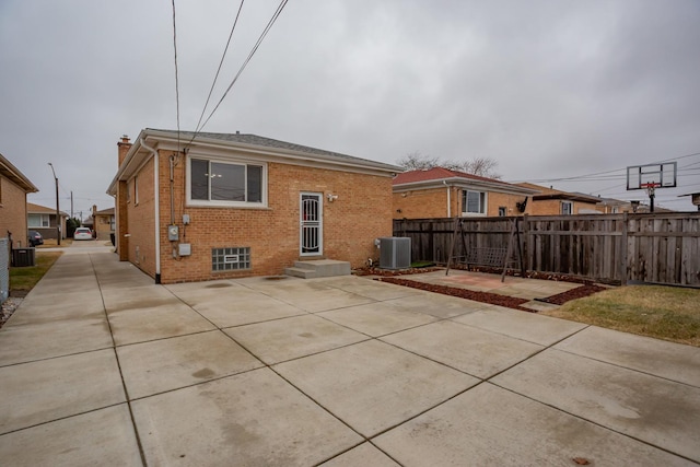 back of property with central air condition unit, fence, a patio, and brick siding