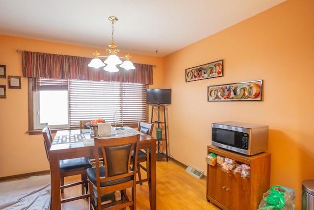 dining room with baseboards, a notable chandelier, visible vents, and light wood finished floors