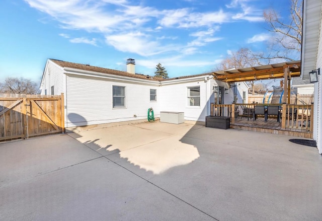 back of house with a patio area, a chimney, a gate, and fence