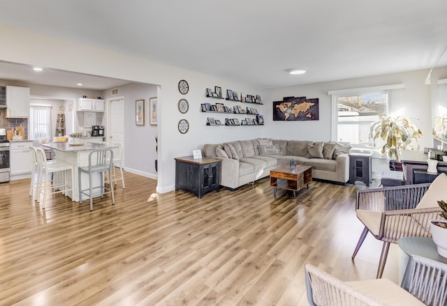 living area featuring baseboards, plenty of natural light, visible vents, and light wood finished floors