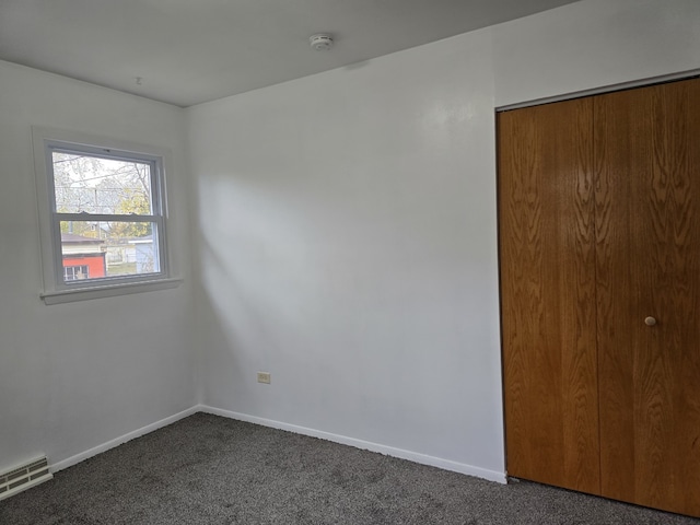 unfurnished bedroom featuring baseboards, visible vents, dark carpet, and a closet