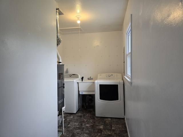 laundry area with laundry area, attic access, stone finish flooring, washing machine and dryer, and a sink