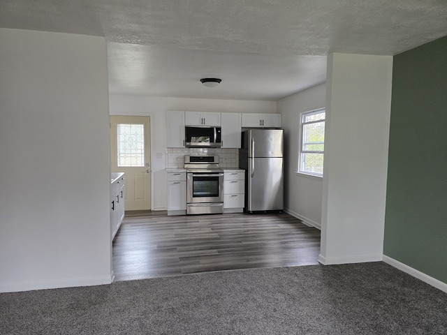 kitchen with baseboards, stainless steel appliances, white cabinetry, dark carpet, and backsplash