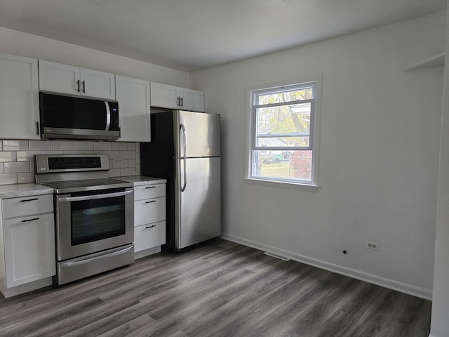 kitchen with light countertops, backsplash, appliances with stainless steel finishes, white cabinets, and wood finished floors