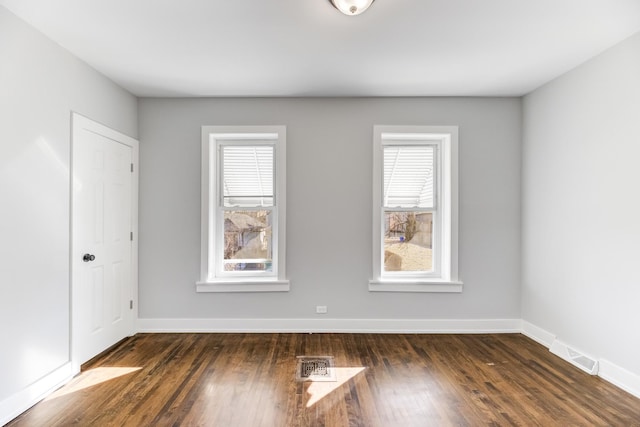 unfurnished room featuring visible vents, baseboards, and hardwood / wood-style floors