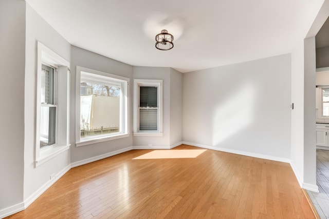 unfurnished room with baseboards and light wood-style flooring