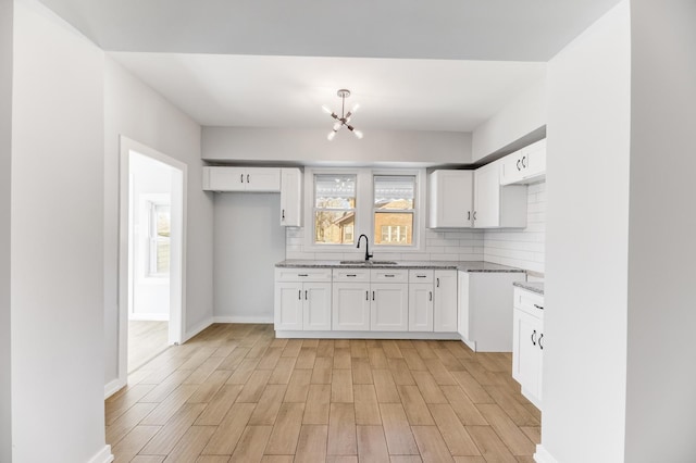 kitchen featuring an inviting chandelier, light stone countertops, backsplash, and a sink