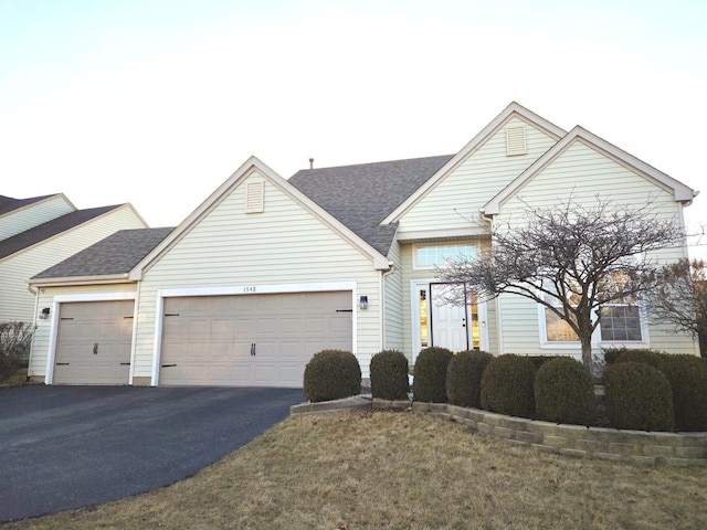 view of front of house with aphalt driveway, roof with shingles, and an attached garage