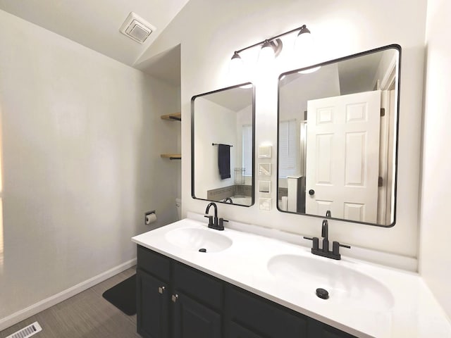 full bath with double vanity, baseboards, visible vents, and a sink