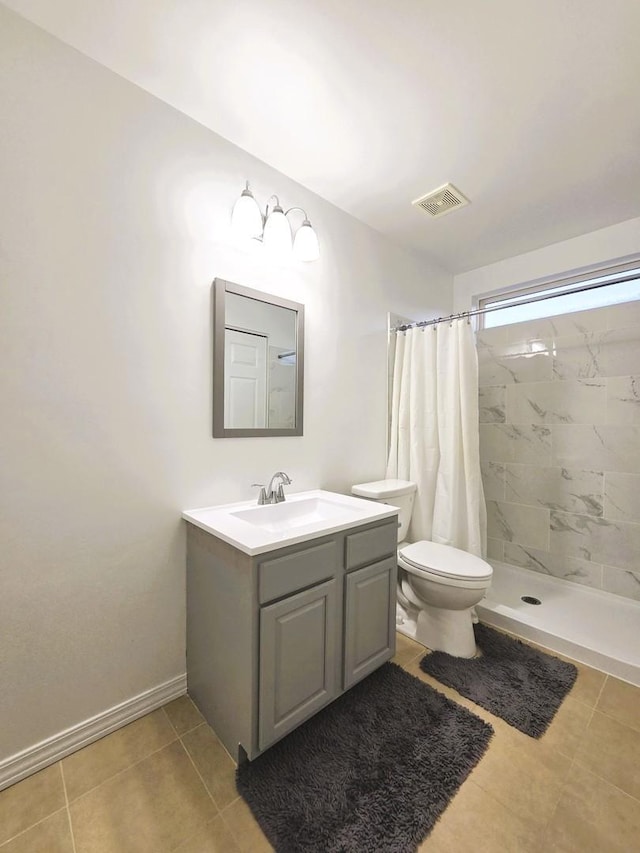 bathroom with vanity, baseboards, visible vents, a tile shower, and toilet