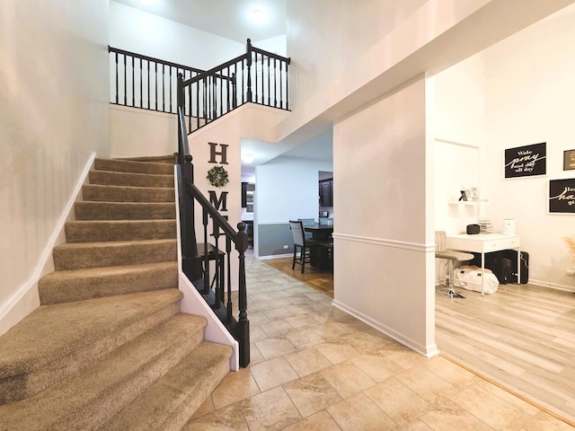 stairs with baseboards, a high ceiling, and wood finished floors