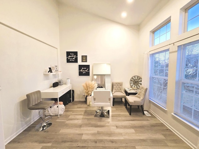 sitting room featuring a high ceiling, baseboards, and wood finished floors