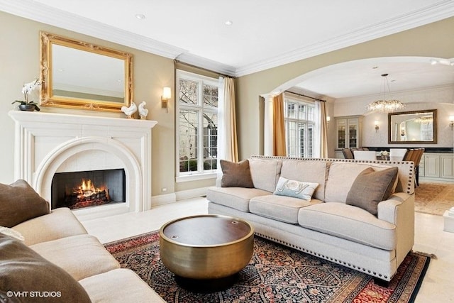 living room featuring arched walkways, crown molding, a premium fireplace, and a chandelier