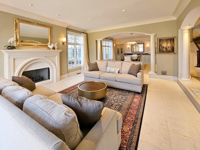 living room featuring decorative columns, arched walkways, ornamental molding, a fireplace, and baseboards