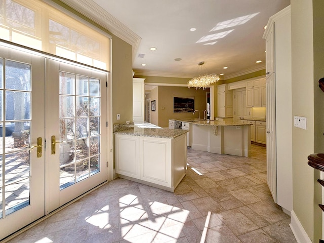 entryway featuring a chandelier, crown molding, healthy amount of natural light, stone tile flooring, and french doors