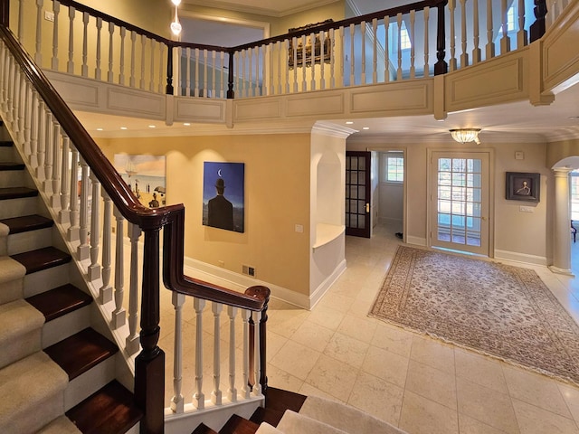 foyer entrance featuring crown molding, baseboards, stairs, ornate columns, and a high ceiling