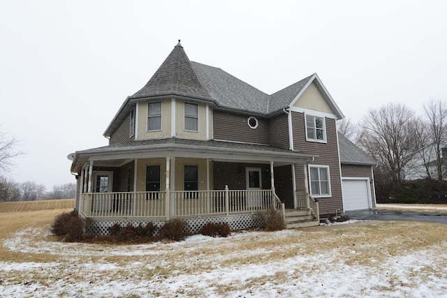 victorian house with an attached garage, covered porch, and a shingled roof