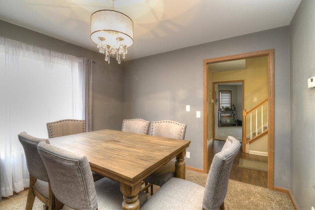 dining space with a chandelier, stairway, and baseboards