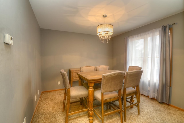 dining space with baseboards, light colored carpet, and an inviting chandelier