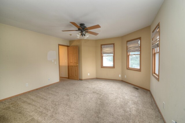 carpeted empty room featuring visible vents, baseboards, and a ceiling fan