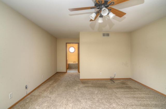 carpeted spare room with visible vents, baseboards, and a ceiling fan