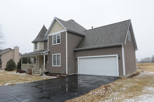 view of front of home with aphalt driveway, an attached garage, and a shingled roof