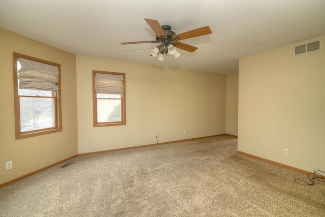 carpeted spare room featuring visible vents, ceiling fan, and baseboards