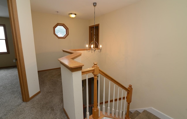 stairs with baseboards, a chandelier, and carpet flooring