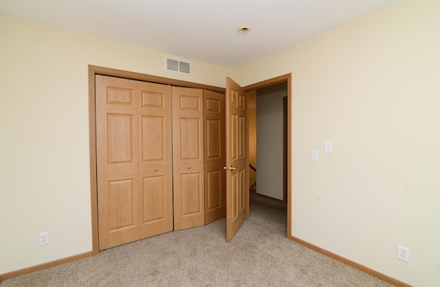 unfurnished bedroom with baseboards, visible vents, a closet, and light carpet