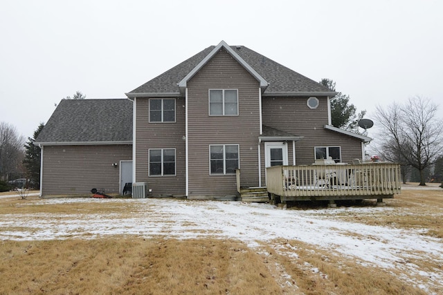 snow covered property featuring a shingled roof, central air condition unit, and a wooden deck