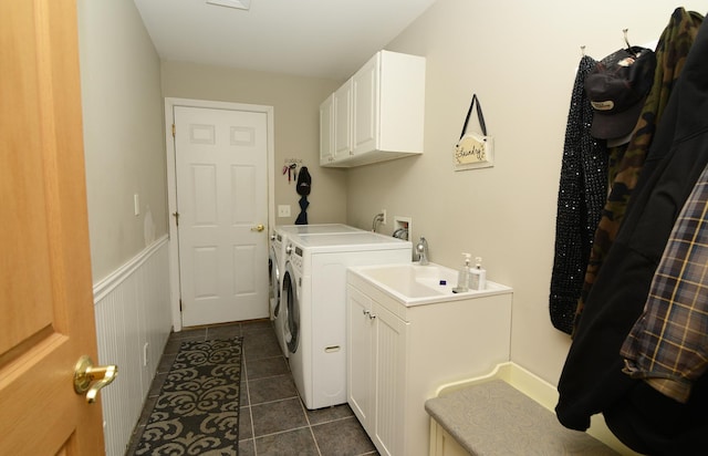 laundry room with washer and clothes dryer, a wainscoted wall, cabinet space, and dark tile patterned flooring