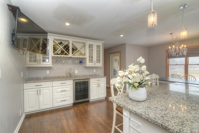 kitchen with dark wood-style floors, glass insert cabinets, an inviting chandelier, and beverage cooler