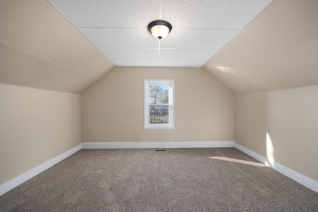 additional living space with vaulted ceiling, carpet, and baseboards